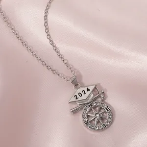 Detail van 2024 afstudeerketting met kompas hanger op roze zijden achtergrond