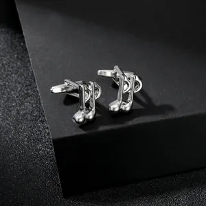 Close-up of polished silver eighth note cufflinks on a black textured display stand