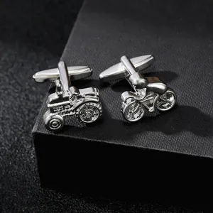 Macro shot of silver metal cufflinks featuring unique tractor and bicycle designs