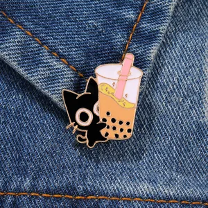 Detail of cartoon black cat boba tea enamel pin on blue denim fabric texture