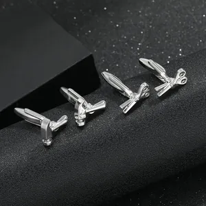 Gemelos plateados con diseño creativo de martillo y tijeras sobre fondo negro