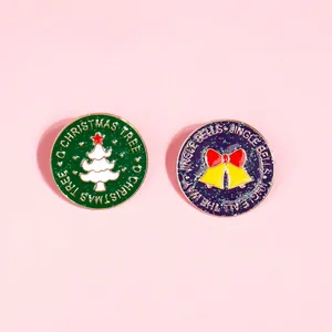 Detail van emaille pins met kerstboom en bellen, met glitters en feestelijke teksten