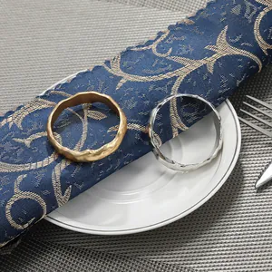 Ronds de serviette modernes en métal or et argent sur une serviette en lin bleu élégante