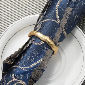 Gros plan d'un rond de serviette en métal doré mat texturé sur serviette bleue