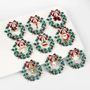 Macro view of nine Christmas brooch styles featuring wreaths and bells on a white tray