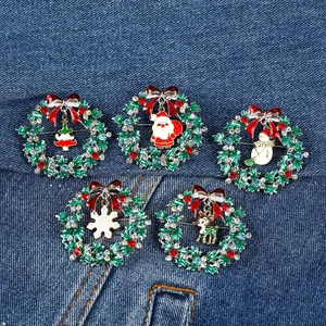Five styles of Christmas wreath brooches with enamel charms on blue denim background