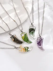 Detail of colorful horn-shaped agate necklaces with silver chains on a decorative plate
