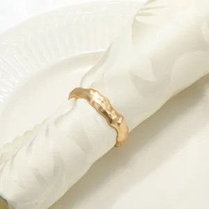 Détail d'un rond de serviette doré mat avec texture martelée sur une serviette blanche