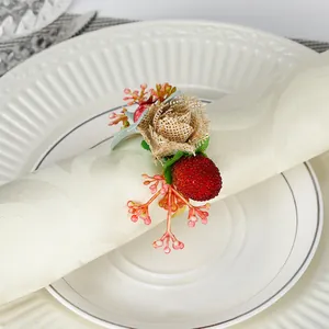 Serviettenring zu Weihnachten mit roten Beeren, Tannennadeln und Juteblume auf Leinen