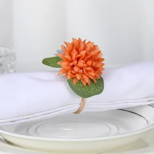 Nahaufnahme vom Serviettenring mit orangefarbener Blume, grünen Blättern und Goldring