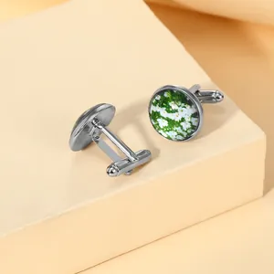Detail shot of silver cufflinks featuring a white daisy pattern on a green background