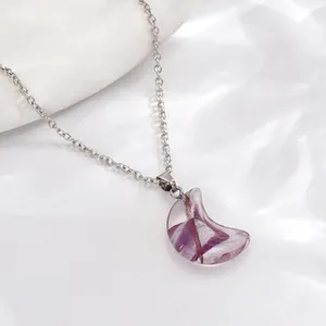 Macro shot of crescent moon pendant with purple textures and elegant silver chain
