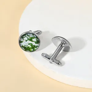 Detailed view of silver cufflinks featuring a white daisy floral inlay and rotating closure