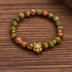 Detailed macro of unakite stone beads and gold alloy wolf head on beaded bracelet