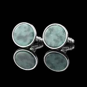 Classic round silver cufflinks with emerald green stone inlay on black reflective surface