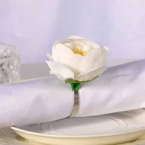 Detalle de rosa blanca artificial y servilletero de metal plateado para decoración