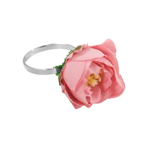 Detalle de servilletero de flor rosa con banda de metal plateado y estambres amarillos