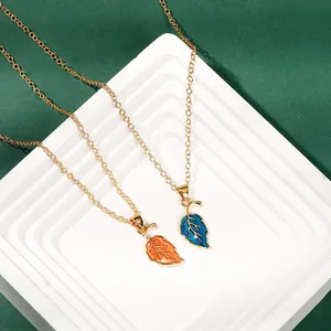 Detail of blue and orange leaf enamel pendants on gold chains for women
