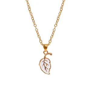 Detailed close-up of a gold-plated leaf pendant with white enamel on a fine cross chain