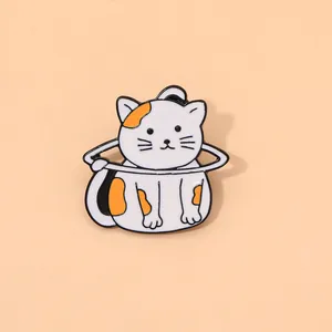 Détail d'une broche chat de dessin animé en émail avec des taches orange sur un anneau