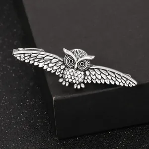 Macro shot of silver owl tie clip showing vintage feather carving and metal details