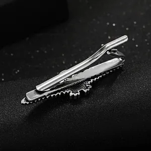 Close-up of silver metal tie clip showing spring mechanism and textured edge detail