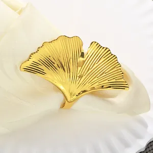 Dettaglio del portatovagliolo dorato a foglia di ginkgo con venature su piatto bianco
