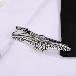 Silver owl necktie clip with detailed feather carving on a white shirt and black suit
