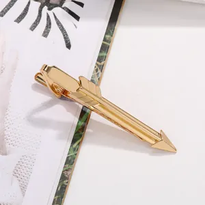 Macro view of gold arrow tie clip with detailed feather texture and polished metallic finish