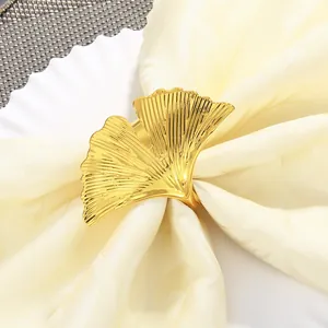 Dettaglio portatovagliolo a foglia di ginkgo dorata con texture su tovagliolo beige