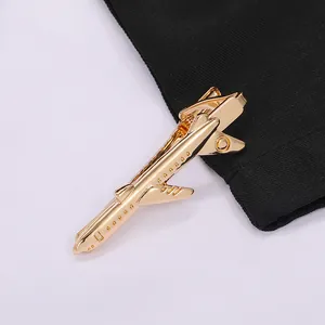 Detailed close-up of a golden airplane-shaped metal tie clip on a black suit fabric