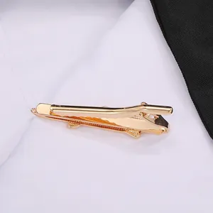 Detail of a polished gold-tone metal tie clip on a classic white shirt and black suit jacket