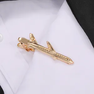 Polished gold airplane tie clip displayed on a white shirt and black suit blazer