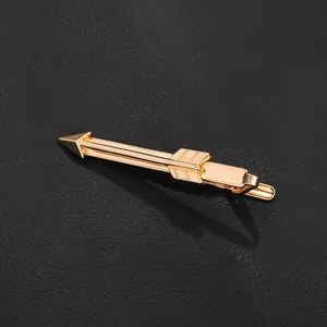 Detailed close-up of a gold-tone arrow-shaped tie clip on a black leather surface