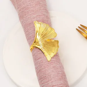 Portatovagliolo a forma di foglia di ginkgo dorata su un piatto di ceramica bianca