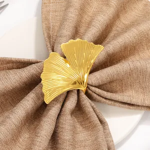 Portatovagliolo in metallo a forma di foglia di ginkgo dorata su tovagliolo marrone