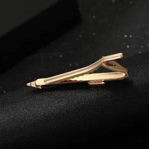 Polished gold pencil-shaped tie clip for men on a dark textured background
