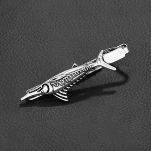 Detailed view of silver swordfish tie clip on dark leather background with intricate textures