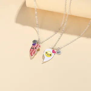 Close-up of BFF heart necklaces with cute cartoon bacon and fried egg enamel pendants