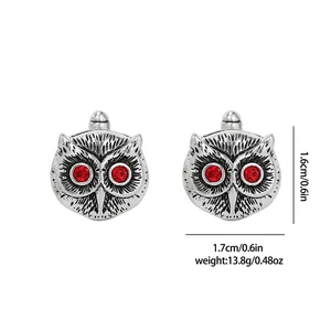 Detailed view of silver owl cufflinks with red crystal eyes and engraved feathers