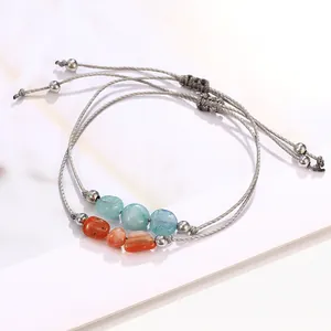 Close-up of handmade woven bracelets with natural blue and orange stones on marble