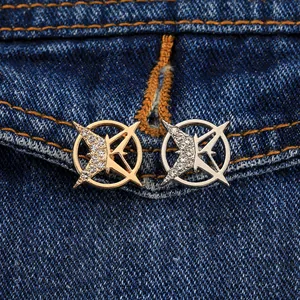 Nahaufnahme von Gold- und Silber-Hexagramm-Broschen mit Kristallen auf Denim-Stoff