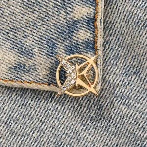 Makroaufnahme einer goldenen Hexagramm-Brosche mit Straß auf hellblauem Denim-Stoff