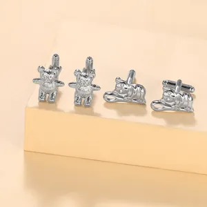 Detailed view of silver bear-shaped cufflinks with rhinestone eyes on beige steps