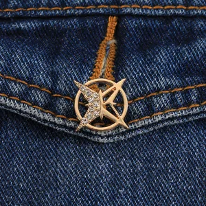 Makroaufnahme einer goldenen geometrischen Sternbrosche mit Strass auf blauem Denim