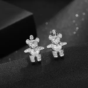 Polished silver bear cufflinks with crystal eyes for men on a black textured base