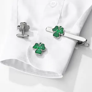 Men's silver cufflinks and tie clip set with green four-leaf clover design on white shirt