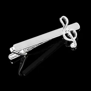 Polished silver tie clip with a musical treble clef design on a black background