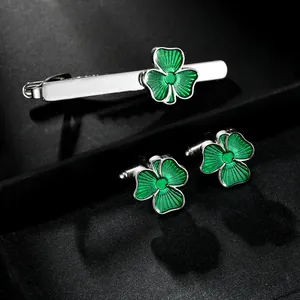 Macro detail of silver tie clip and cufflinks set with green enamel clover pattern