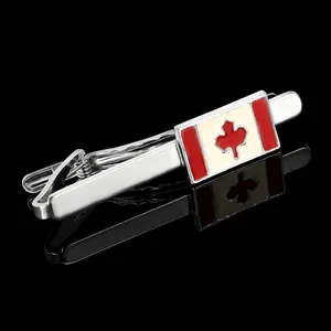 Close-up of a silver tie clip with Canada flag maple leaf on a black reflective surface